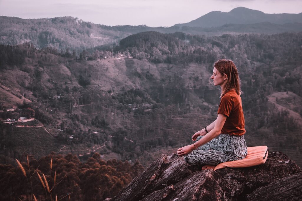 woman meditating on top of the hill