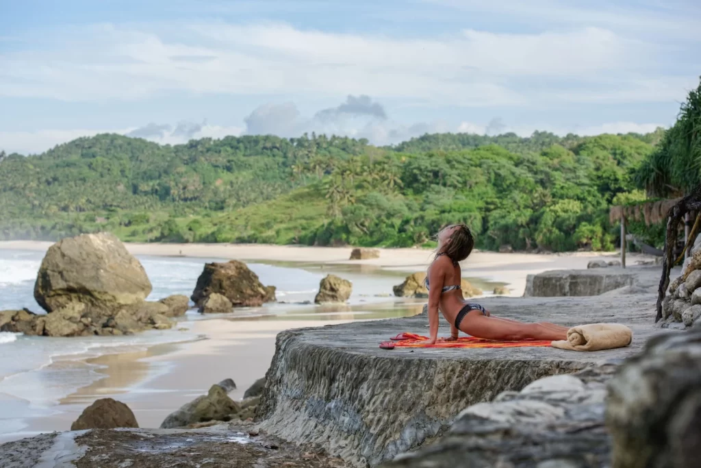 woman practicing yoga on the beach